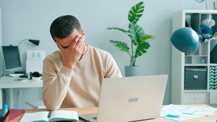 Hombre estresado frente a la computadora buscando servicios de inmobiliarias en Venezuela